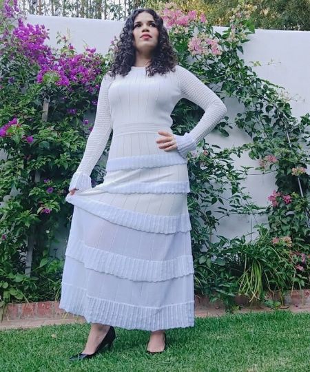 America Ferrera in a white top poses for a picture.